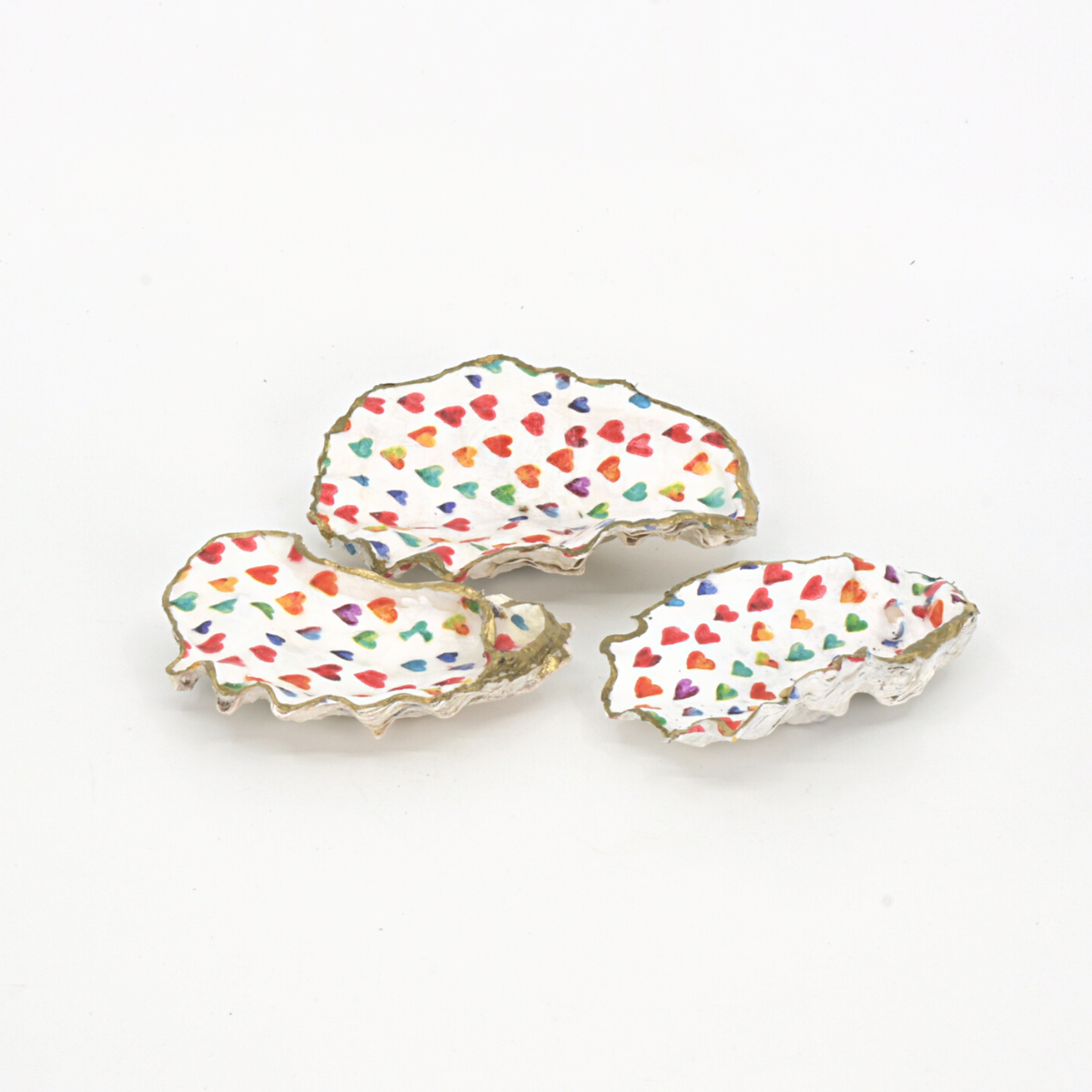 Set of three decoupaged oyster shells in rainbow heart paper and painted gold trim, made by Salt Spring Island artist Cathie Grindler. 