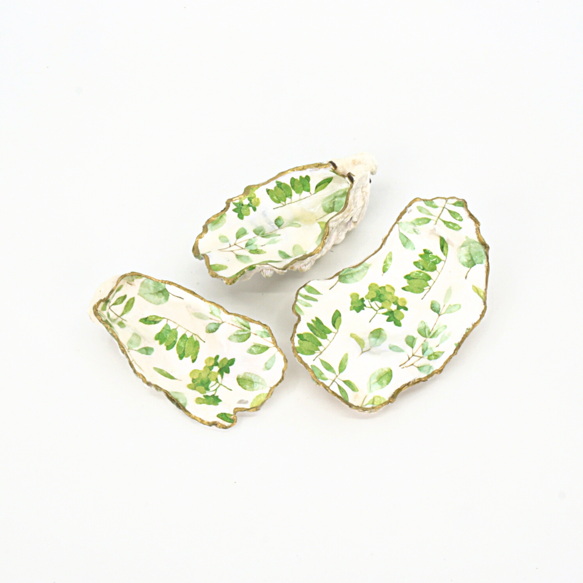 Set of three decoupaged oyster shells with painted gold trim, made by Salt Spring Island artist Cathie Grindler. 